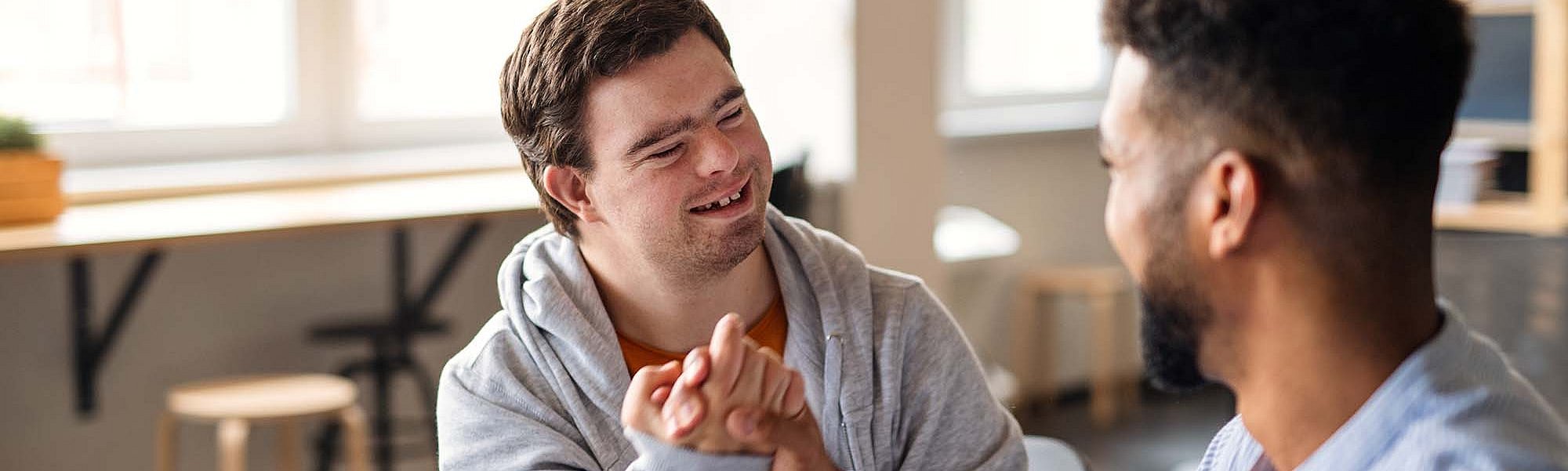 Zwei Männer, einer davon mit Down Syndrom, machen einen Bro-Handshake